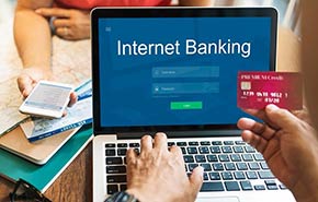 A man using a credit or debit card for his online banking on a laptop computer